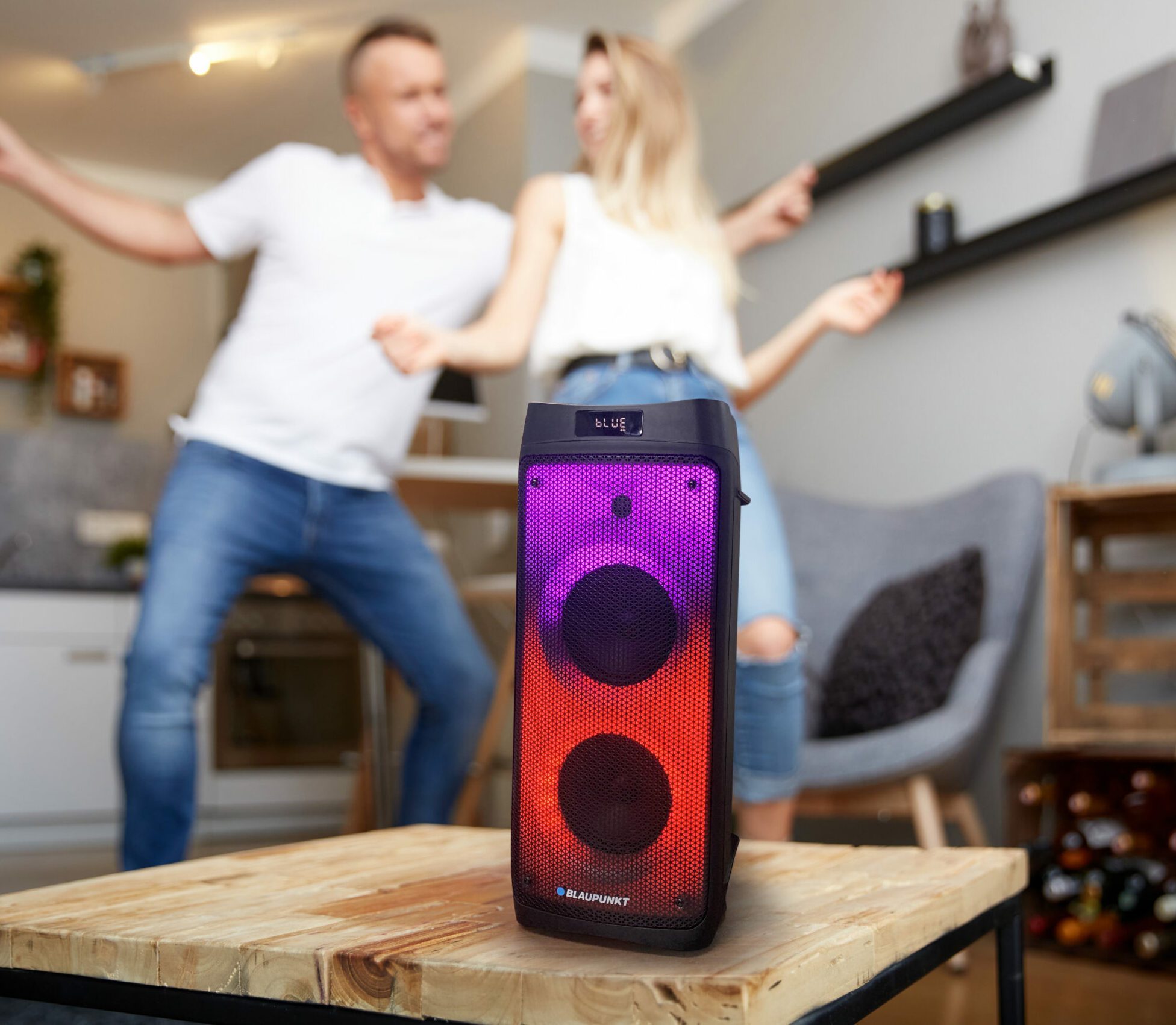 Close-up,Of,Smart,Speaker,On,Wooden,Table,Against,Happy,Couple
